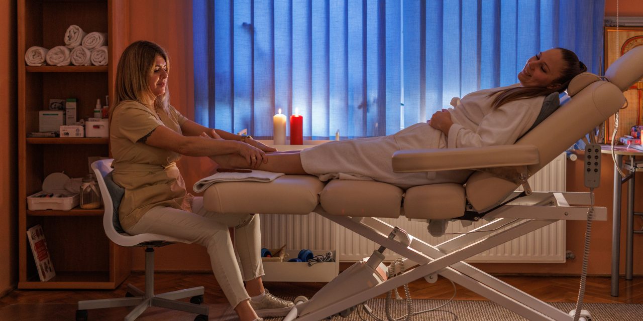 Lábmasszázs egy harmonikus kezelőhelyiségben, gyertyafénnyel és nyugodt környezettel
